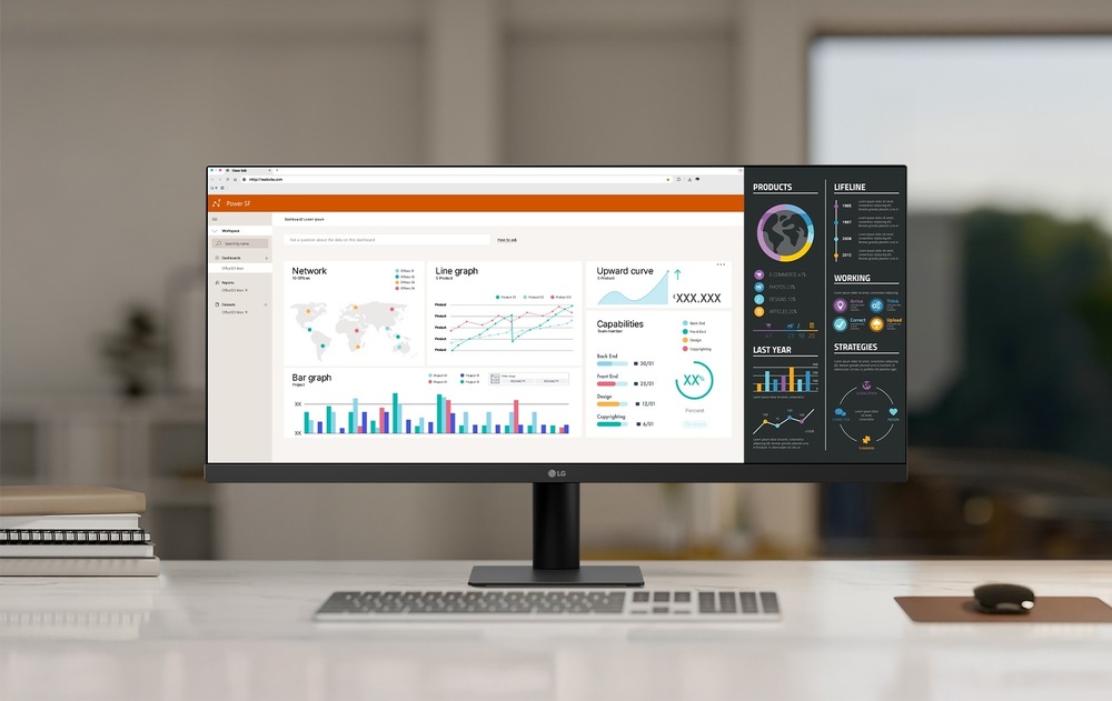 Moderní kancelářský stůl s ultraširokoúhlým monitorem zobrazujícím analýzy dat. Displej zobrazuje grafy, tabulky a mapy.