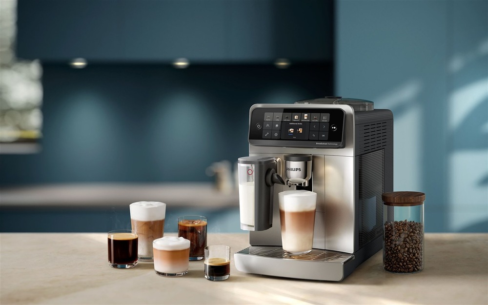 Automatický kávovar Philips připravující mléčný kávový nápoj, doplněný několika druhy kávy a nádobou s kávovými zrny