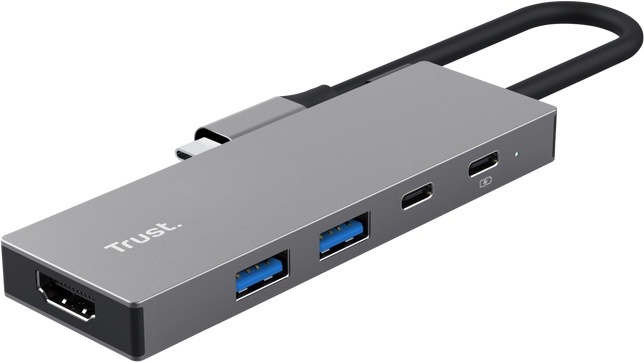 USB Hub Trust DALYX 5v1 stříbrný Na obrázku je stříbrný USB-C hub Trust DALYX 5v1 zachycený šikmo zepředu. Má úzké kovové tělo s jednoduchým hranatým designem a z jednoho konce z něj vede krátký kabel zakončený USB-C konektorem. Na levém čele je HDMI konektor, na boku dva modré USB porty a dva menší USB-C porty, vedle kterých je malá kontrolka.