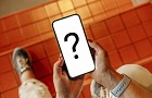 Displej telefonu s otazníkem. Telefon někdo drží v rukou. V pozadí je podlaha s kachličkami.