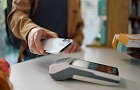 Muž přikládá mobilní telefon k platebnímu terminálu.