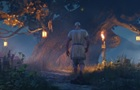 Geralt kráčí ke stromu ověšenému světly, vlevo je hořící oheň